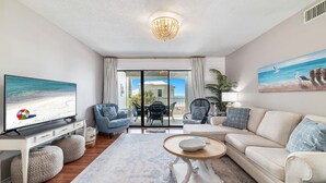 A living room with a television, sofas, chairs, a coffee table, and a view of the outdoors.