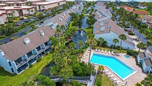 Un complexe hôtelier doté d’une piscine, de palmiers et offrant une vue sur l’océan.