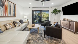 Un salon moderne comprenant un canapé, un fauteuil, une table basse et un grand tableau.