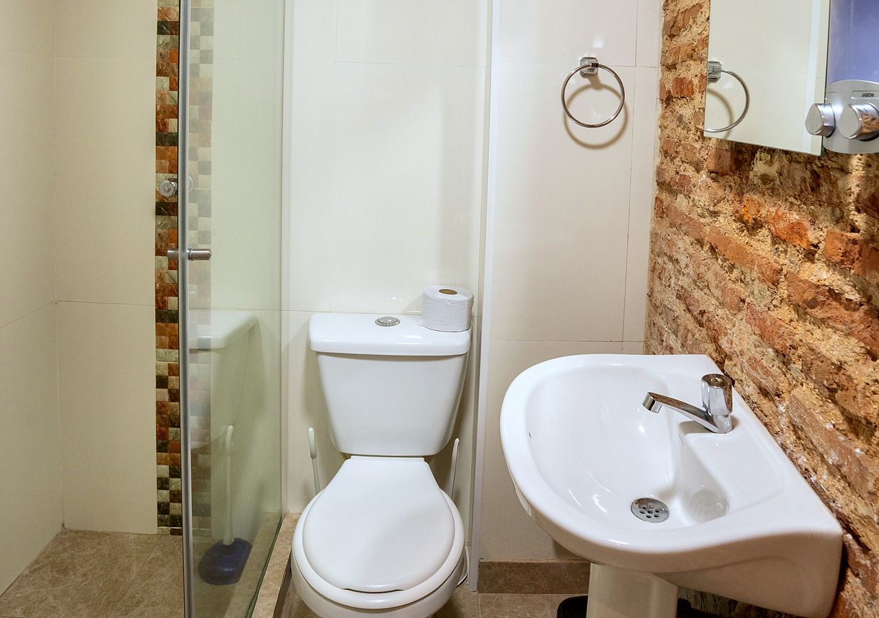Casa de banho com sanita, cabine de duche em vidro e lavatório com espelho em cima.
