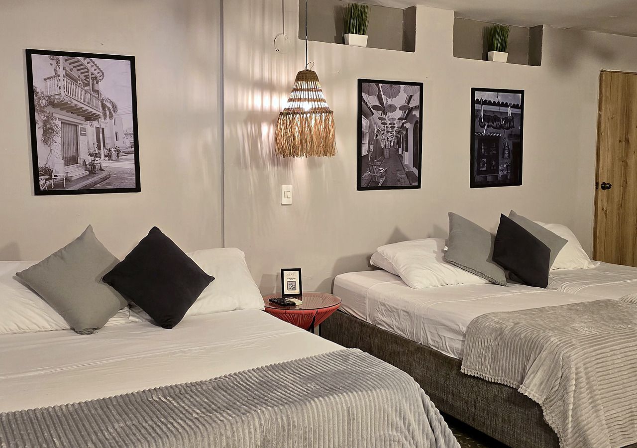 A hotel room with two beds, a red side table, and a hanging light fixture.