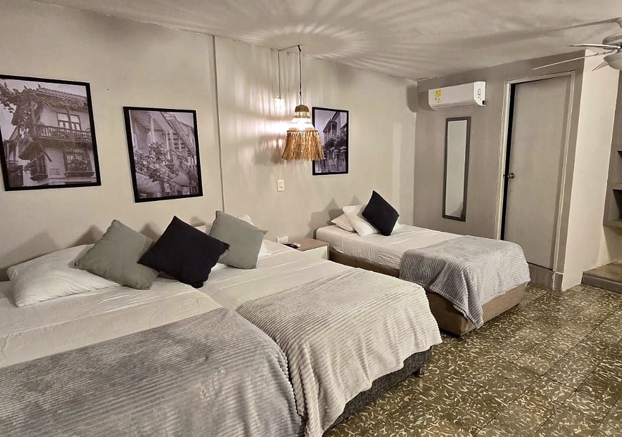 Ein Hotelzimmer mit zwei Betten, einer Pendelleuchte und einer Tür mit Spiegel.