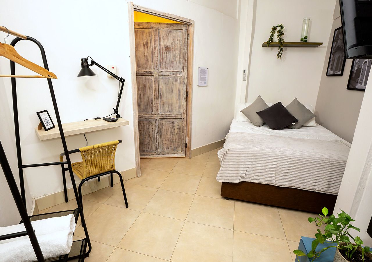 Un dormitorio pequeño con cama, mesita de noche, lámpara y una silla.