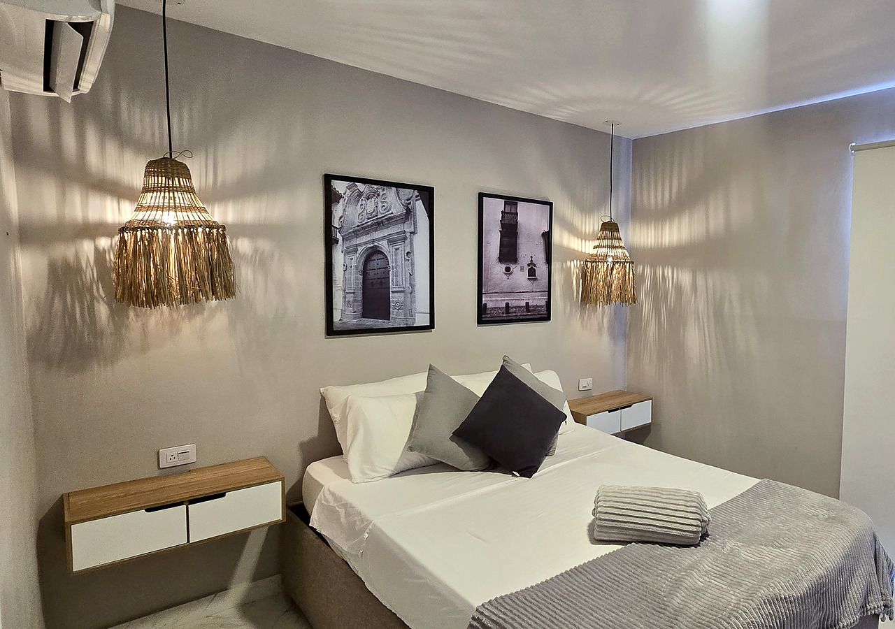 Een slaapkamer met een bed, nachtkastjes en wandlampen.