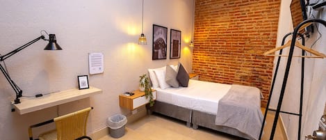 Ein gemütliches Schlafzimmer mit Bett, Nachttisch, Lampe und einem Hängekorbstuhl.