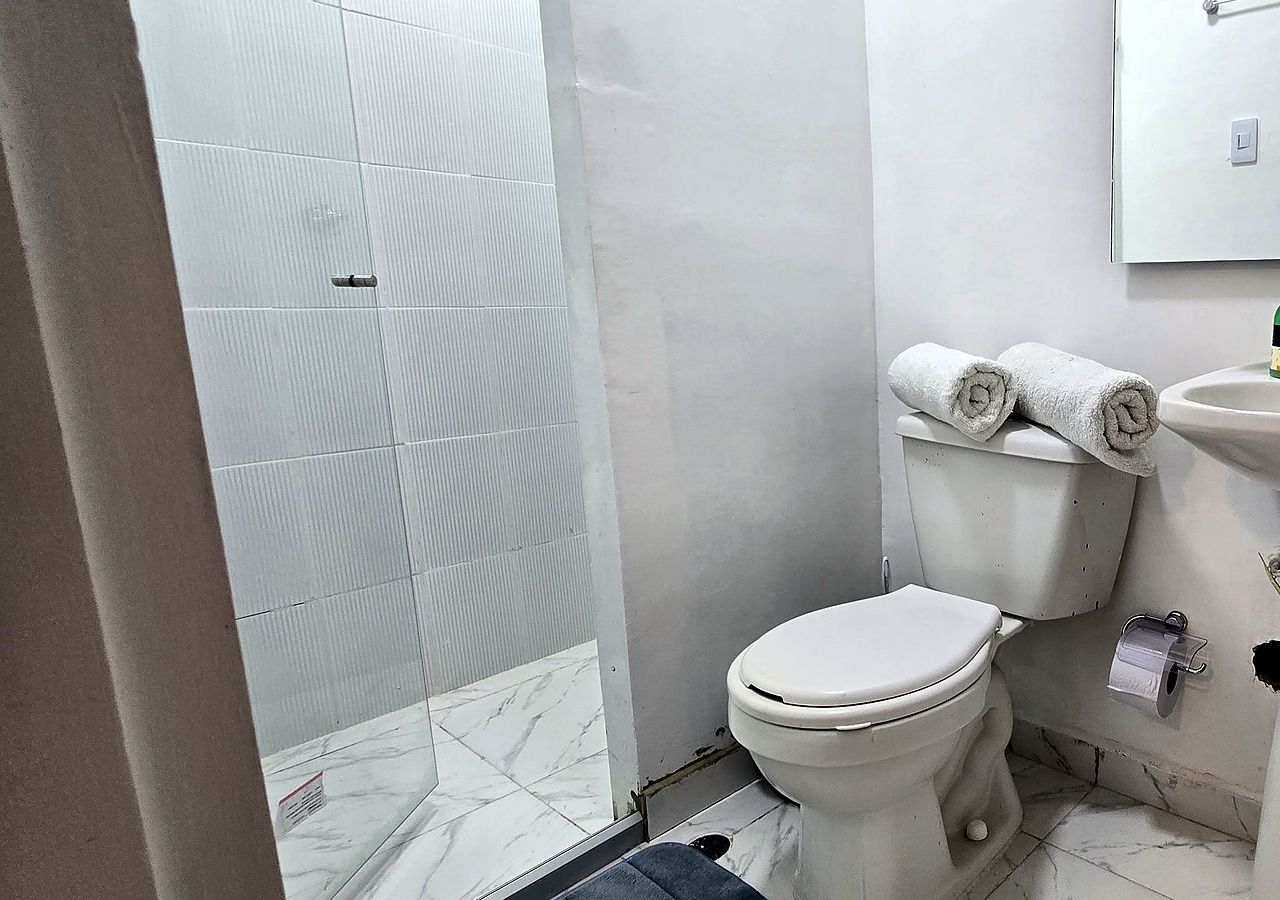 Un baño con inodoro, lavamanos y zona de ducha.