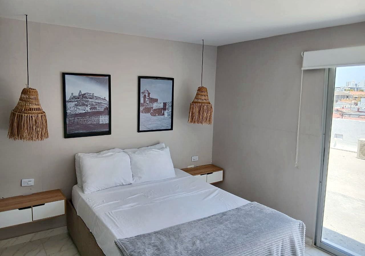 Ein Schlafzimmer mit einem Bett, zwei Wandlampen und zwei gerahmten Bildern.