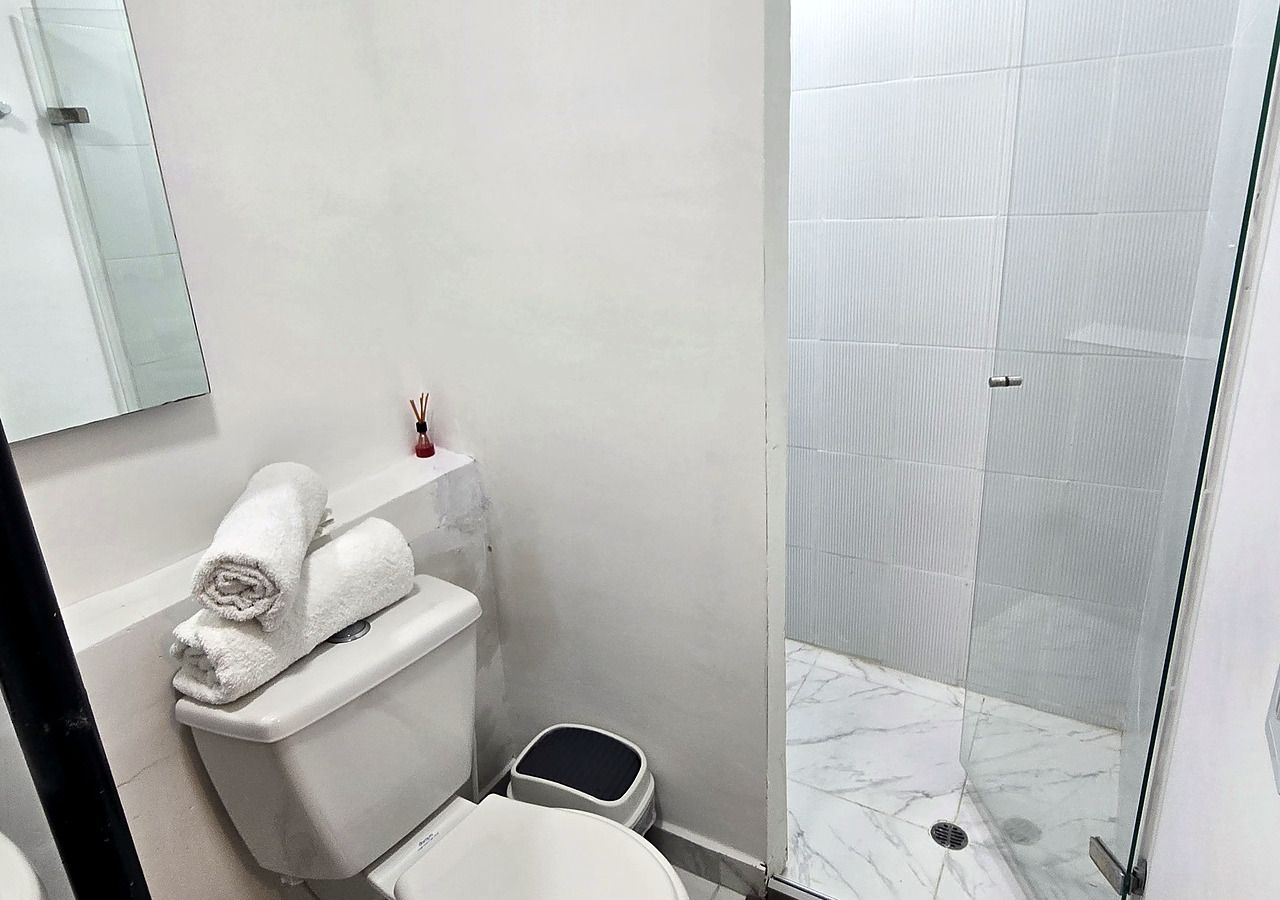 A bathroom with a toilet, a bidet, a glass shower enclosure, and a marble floor.