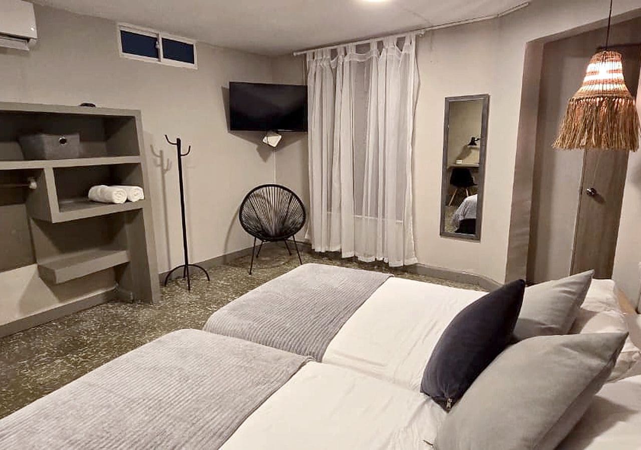 Een hotelkamer met een bed, een aan de muur bevestigde televisie, een stoel en een kledingkast.