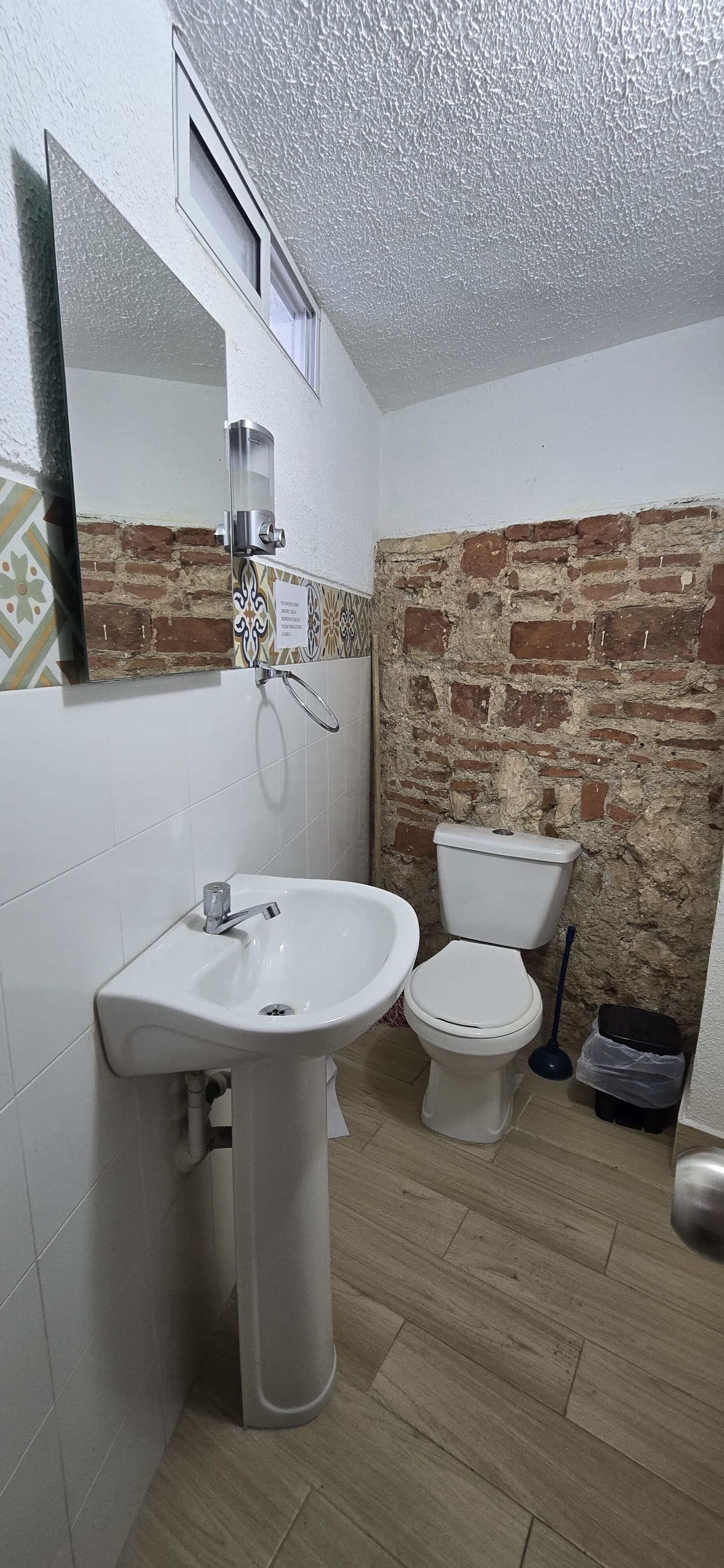 A bathroom with a white sink, a toilet, and a mirror.