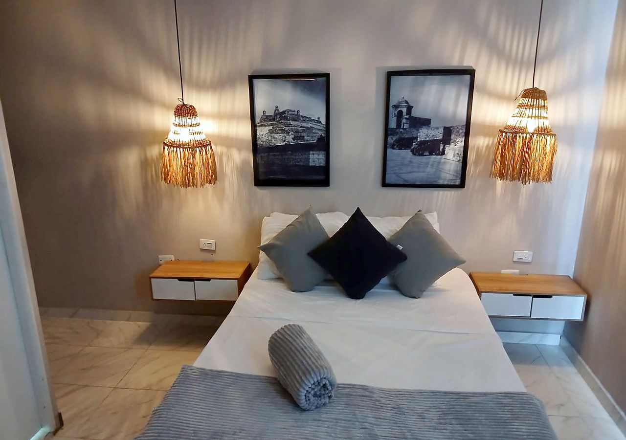 A modern bedroom with a large bed, bedside tables, and two wall-mounted lamps.