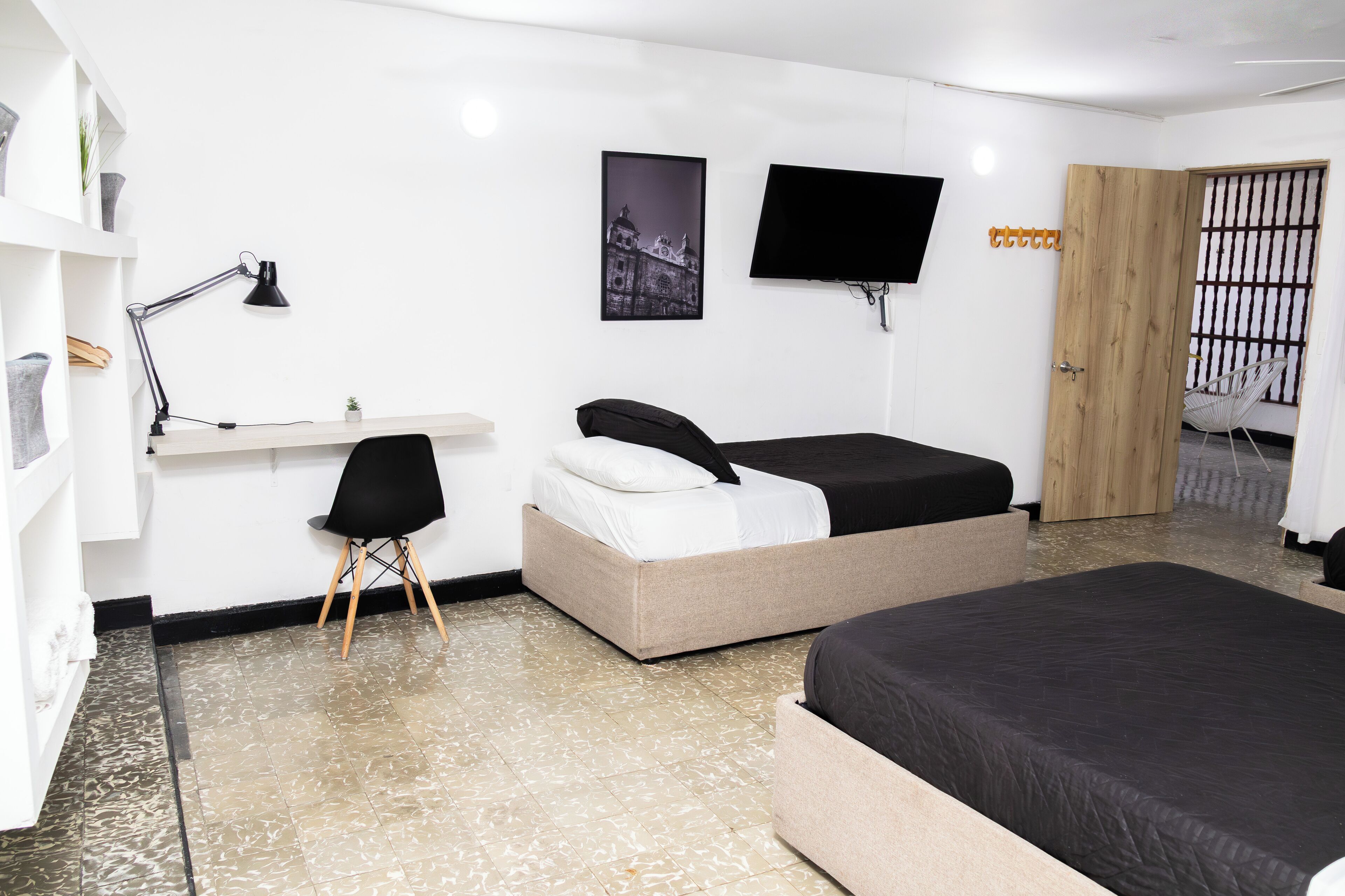 A modern hotel room with a bed, desk, chair, and a TV.