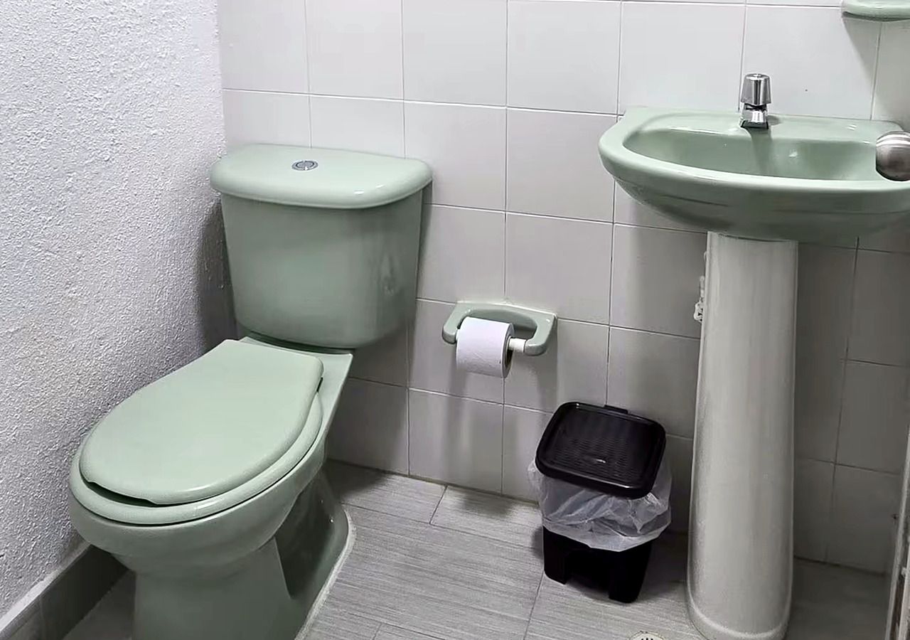 Une petite salle de bain avec des toilettes, un lavabo et une poubelle.