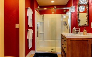 Bathroom features a glass-enclosed shower, wooden vanity, and ornate mirror.