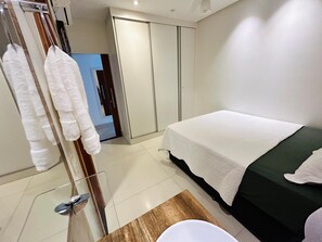 Een hotelkamer met een bed, een houten nachtkastje, een spiegel en een kledingkast.