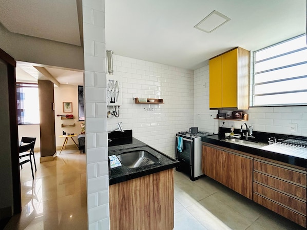 A modern kitchen with white subway tiles, wooden cabinets, and a black countertop.