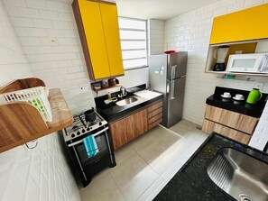 Une cuisine équipée d’une cuisinière à gaz, d’un four, d’un évier, d’un réfrigérateur et d’un four à micro-ondes.