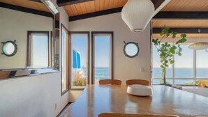 Ein Essbereich mit einem Holztisch, Stühlen und einem großen Fenster mit Meerblick.