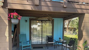 Un patio abrité avec une table et des chaises, une jardinière suspendue et des plantes en pot.