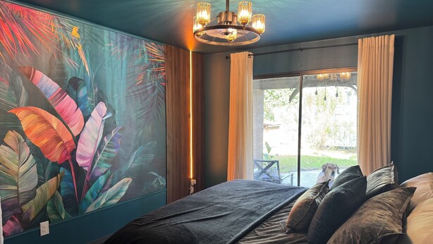 Une chambre avec un grand lit, un luminaire au plafond et une vue sur l’extérieur par une fenêtre.