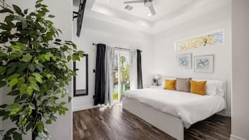 Une chambre à coucher avec un lit, un ventilateur de plafond, une fenêtre avec des rideaux et une plante.