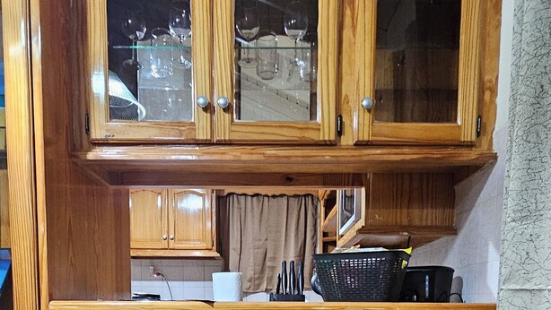 Una cucina con mobili in legno, un piano di lavoro e due sedie nere.