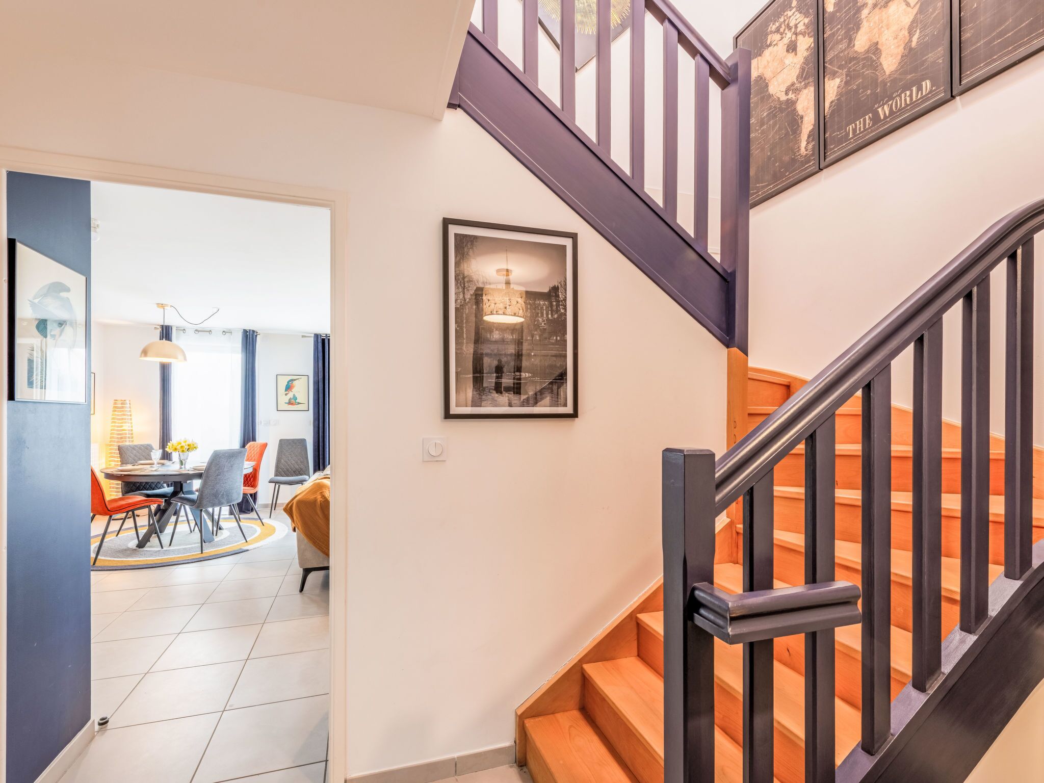 A staircase with a wooden handrail and a black metal railing. There is a framed picture on the wall above the stairs.