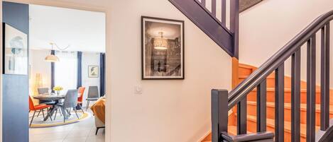 A staircase with a wooden handrail and a black metal railing. There is a framed picture on the wall above the stairs.