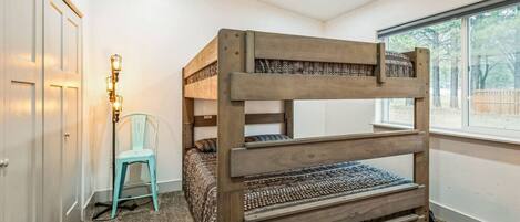 A bunk bed in a room with a window, a chair, and a lamp.