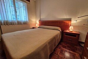Une chambre d’hôtel avec un lit, deux tables de chevet avec des lampes, une tête de lit en bois et un radiateur.