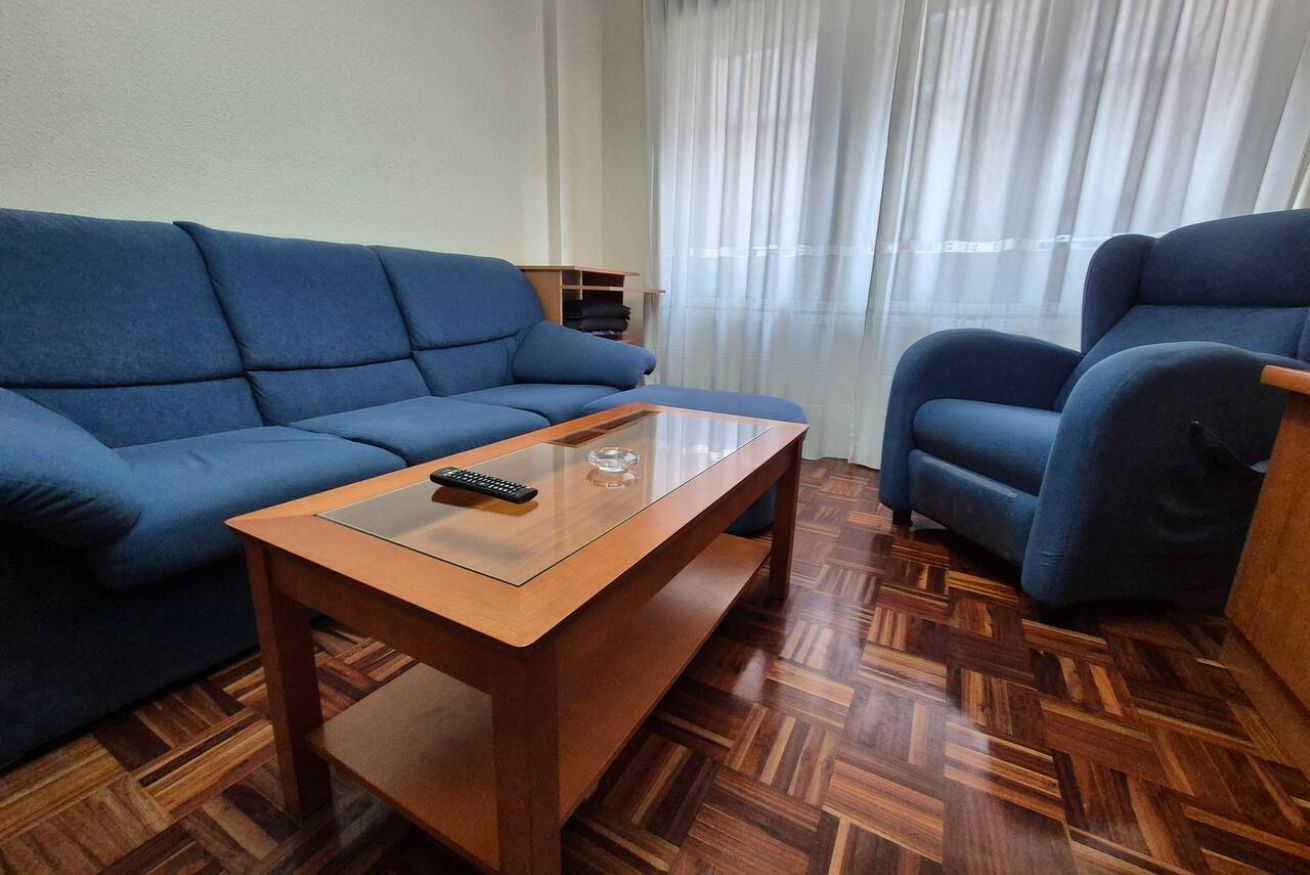 A living room with a blue sofa, a wooden coffee table, and a blue armchair.