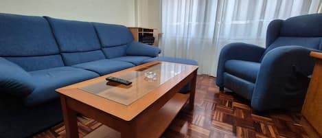 A living room with a blue sofa, a wooden coffee table, and a blue armchair.