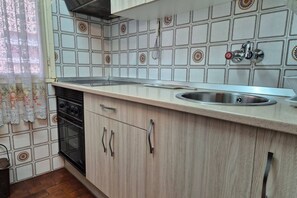 A kitchen with a stove, oven, sink, and light-colored cabinets.