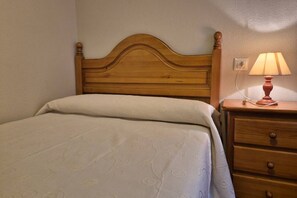 A bed with a wooden headboard, a bedside lamp, and a nightstand with drawers.