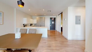 A modern kitchen with white cabinets, a central island, and a dining area with a wooden table and chairs. - Spacious Luxury Beachside Condo with Rooftop Pool-CS69 (Hollywood)