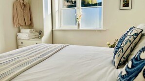 Une chambre avec un lit, une fenêtre donnant sur un beau paysage, une table de chevet avec des serviettes et un peignoir suspendu.