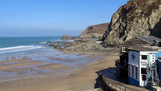 Un café de plage offrant une vue sur l’océan et une falaise rocheuse.