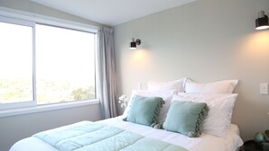 Un dormitorio con una cama grande, una ventana y una lámpara fijada a la pared.