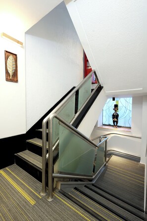 A modern staircase with glass railings and a patterned carpet. - Myotel - Santacruz (Mumbai)