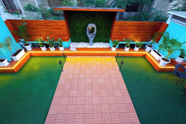 A reception area with a wooden bench, a green artificial turf, and potted plants. - Myotel - Santacruz (Mumbai)