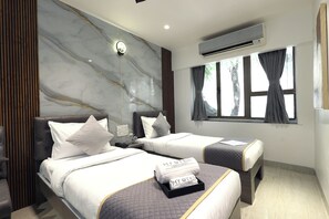A hotel room with two beds, a marble wall, an air conditioner, and a window with curtains. - Myotel - Santacruz (Mumbai)