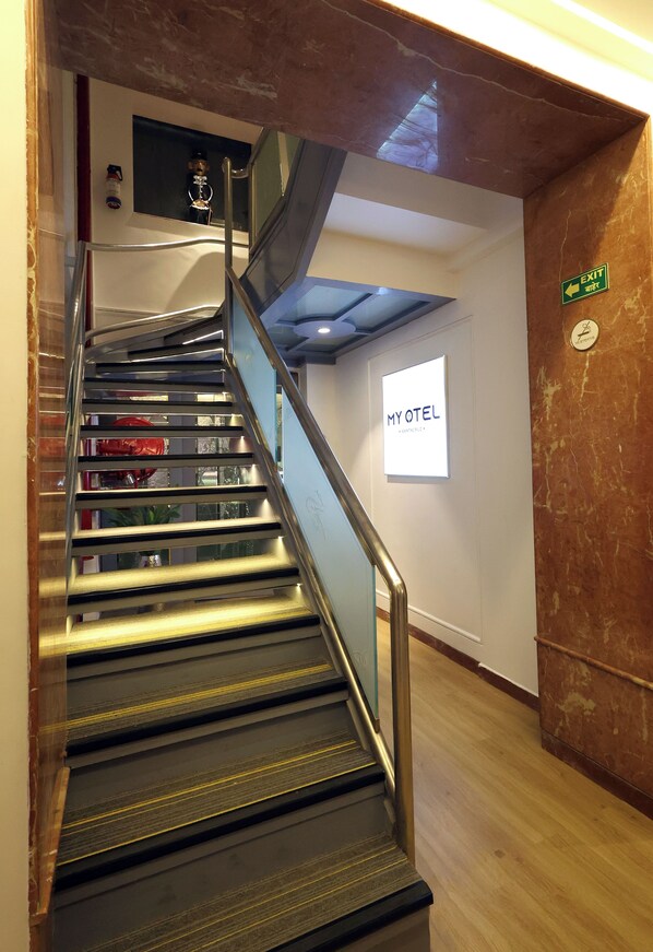 Een trap met een leuning, een bord dat een uitgang aangeeft, en een muur met een bord waarop 'MYOTEL' staat.