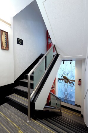 A staircase with a glass railing, a sign indicating a terrace garden, and a fire extinguisher on the wall. - Myotel - Santacruz (Mumbai)