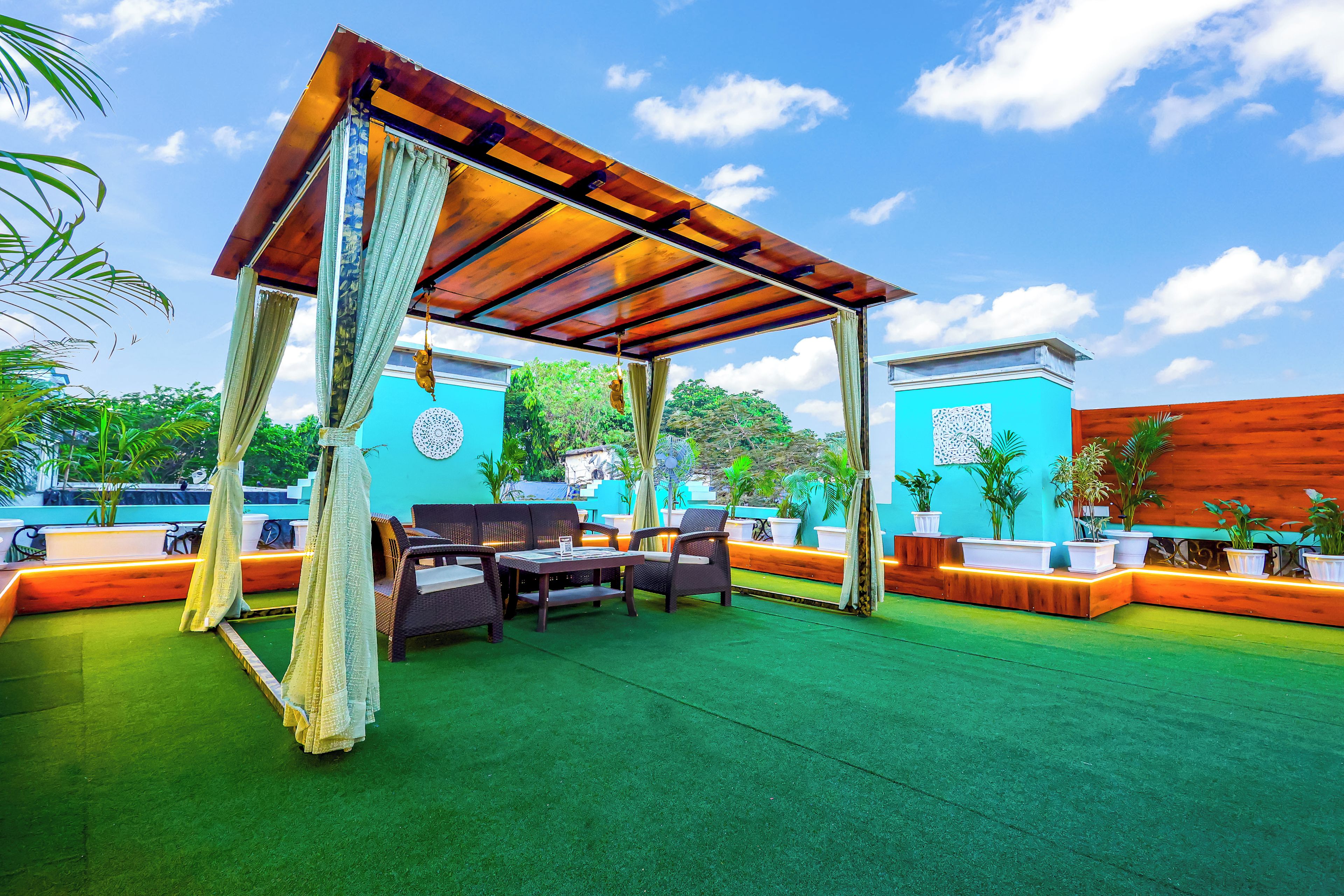 An outdoor seating area with a wooden pergola, green artificial turf, and wicker furniture.