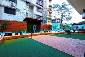 A courtyard with artificial grass, potted plants, and a wooden bench. - Myotel - Santacruz (Mumbai)