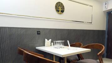 A dining area with a table and chairs, a wall-mounted artwork, and a sign indicating room number T1.