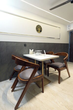 A dining area with a table and chairs, a wall-mounted artwork, and a sign indicating room number T1. - Myotel - Santacruz (Mumbai)