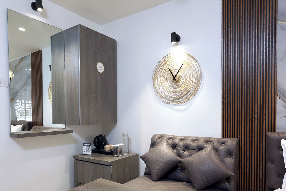 A modern bedroom with a bed, a bedside table, a wall clock, and a mirror.