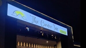 Entrada de un hotel con un cartel que dice "The Corner Inn LODGE".