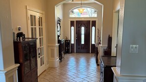 A spacious hallway with a tiled floor, a wooden cabinet, and a stained glass lamp. - 3-bedroom golf course home on Walden on Lake Conroe Montgomery with WiFi, AC (Montgomery)